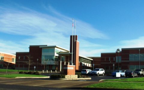 Century High School's brick entrance and flagpoles under a blue sky