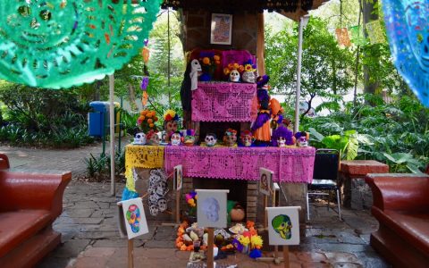 A Día de Muertos altar with sugar skulls, flowers and papel picado banners