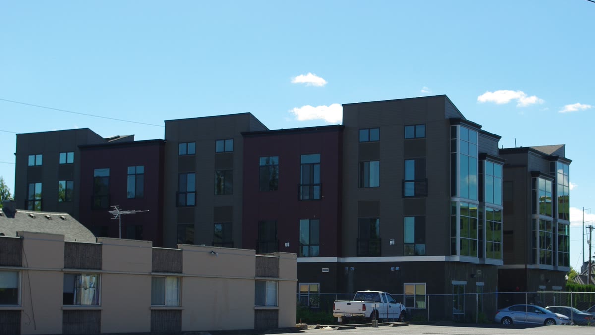 A four-story apartment building behind a one-story building in downtown Hillsboro