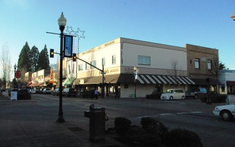 A downtown Hillsboro street corner with a lamp post, storefronts and parked cars