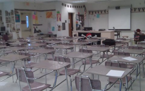 Rows of empty student desks in a high school classroom
