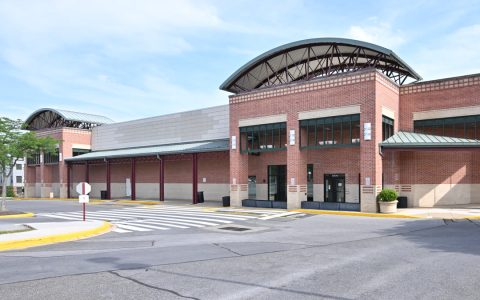 A vacant brick big-box storefront with an arched roof at a shopping center