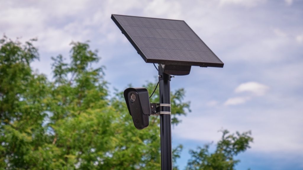A pole-mounted Flock Safety license plate reader camera with a solar panel