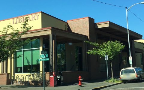 The Forest Grove City Library at a street corner with Pacific Ave and Birch St signs