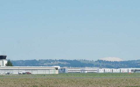The Hillsboro Airport control tower and hangars across an open field, with Mount St. Helens on the horizon