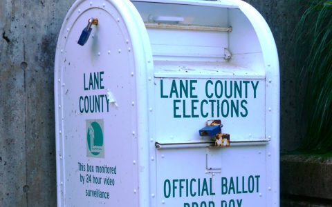 A white metal official ballot drop box labeled Lane County Elections