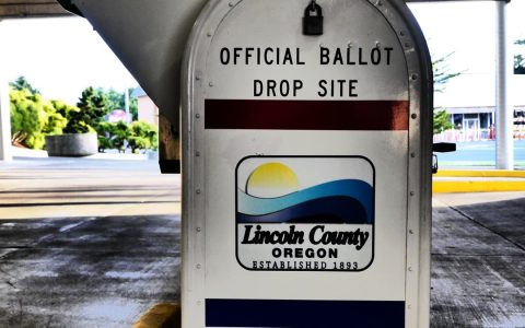 A white metal box labeled Official Ballot Drop Site under a covered entrance