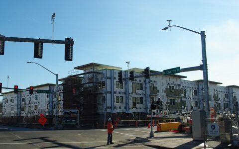 A four-story apartment building in house wrap under construction at an Orenco Station intersection