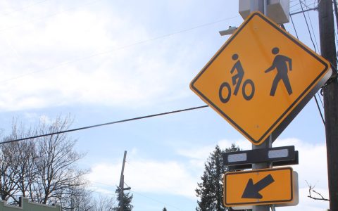 A yellow bicycle and pedestrian crossing sign above a pair of rectangular flashing beacons