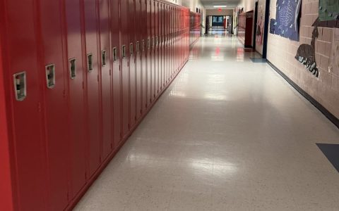 A long empty school hallway lined with red lockers