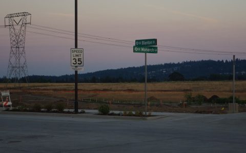 Green street-name signs and a 35 mph sign beside open fields at dusk