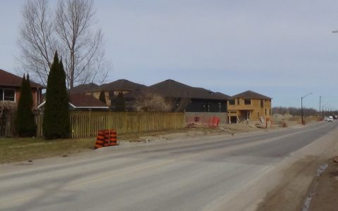 A road lined with finished and half-built houses in a new subdivision